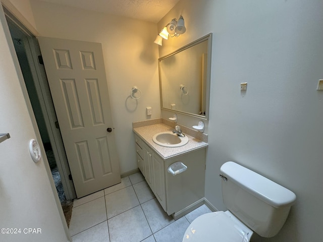 bathroom with vanity, toilet, a textured ceiling, and tile patterned floors