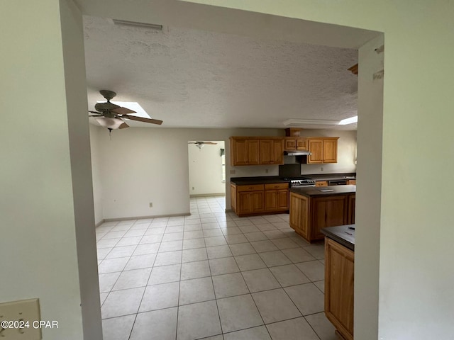 kitchen featuring ceiling fan, stainless steel range, a textured ceiling, and light tile patterned flooring