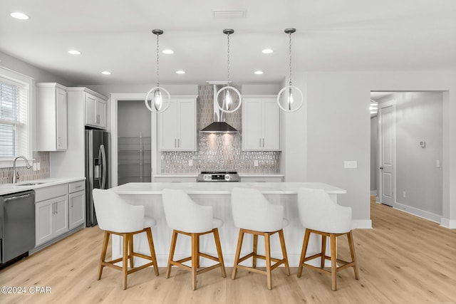 kitchen featuring sink, stainless steel appliances, a center island, and wall chimney exhaust hood