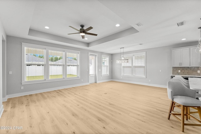 interior space with white cabinetry, backsplash, a raised ceiling, and ceiling fan