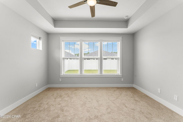 spare room with light carpet, ceiling fan, and a tray ceiling