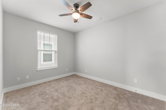 spare room featuring light colored carpet and ceiling fan