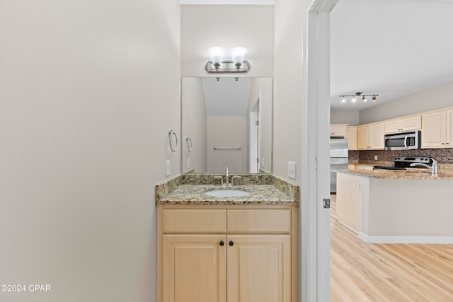 bathroom with wood-type flooring, vanity, and decorative backsplash