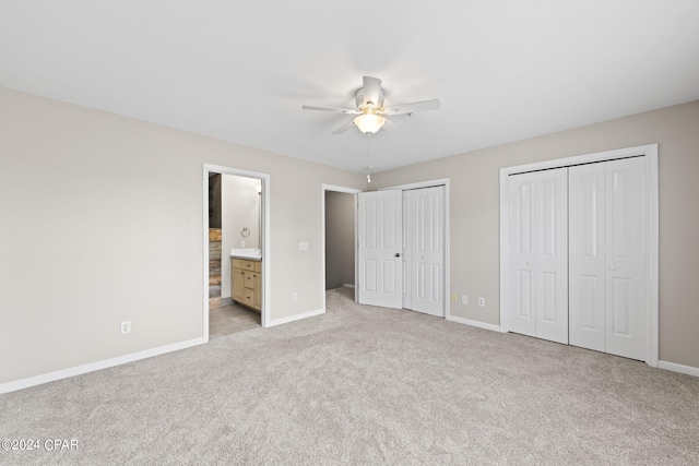 unfurnished bedroom with connected bathroom, two closets, ceiling fan, and light colored carpet