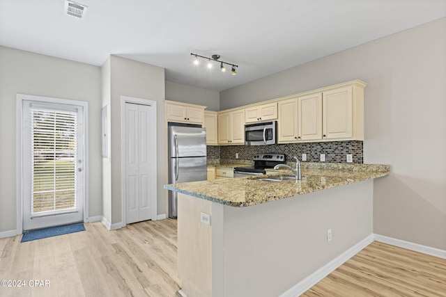 kitchen featuring light stone counters, light hardwood / wood-style floors, tasteful backsplash, kitchen peninsula, and appliances with stainless steel finishes