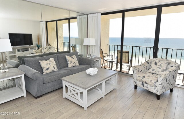 living room with a wall of windows, light hardwood / wood-style floors, and a water view