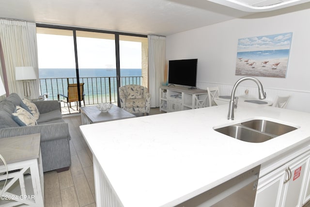 kitchen featuring light countertops, light wood-style flooring, floor to ceiling windows, a sink, and open floor plan