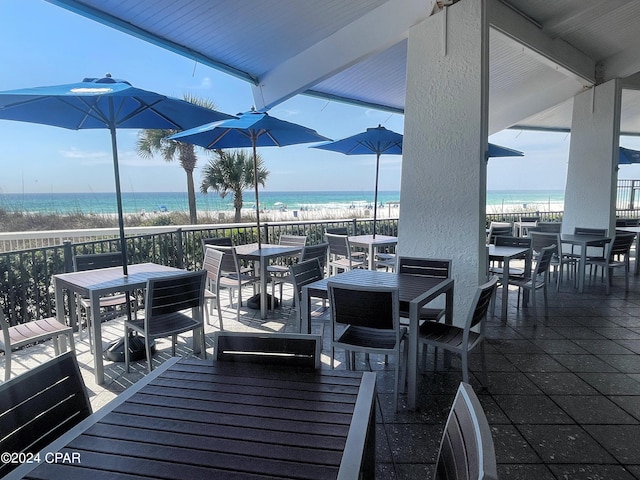 view of patio featuring a beach view, outdoor dining area, and a water view