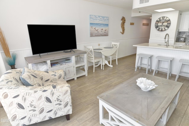 living area featuring a wainscoted wall, light wood-style floors, and visible vents