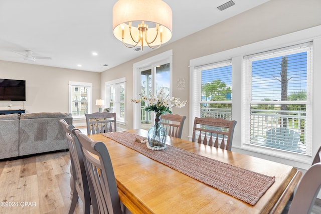 dining space with ceiling fan with notable chandelier, light hardwood / wood-style floors, and a healthy amount of sunlight