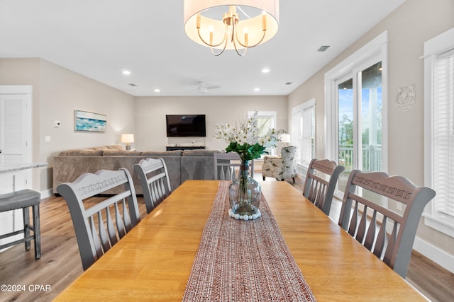 dining area with ceiling fan with notable chandelier and hardwood / wood-style flooring