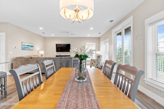 dining room with light wood-type flooring and ceiling fan with notable chandelier