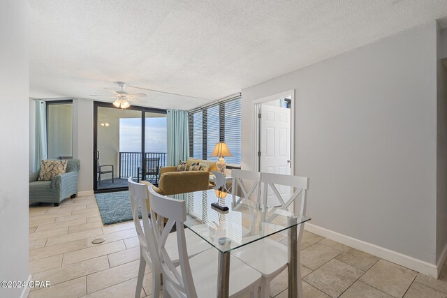 dining space featuring ceiling fan, a wall of windows, and a textured ceiling