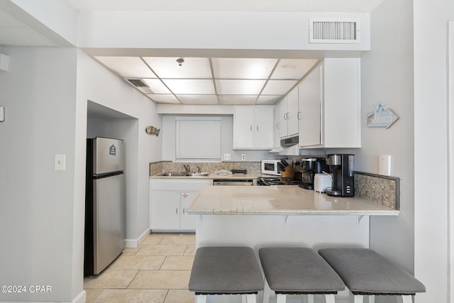 kitchen featuring light tile patterned floors, sink, kitchen peninsula, white cabinetry, and stainless steel appliances