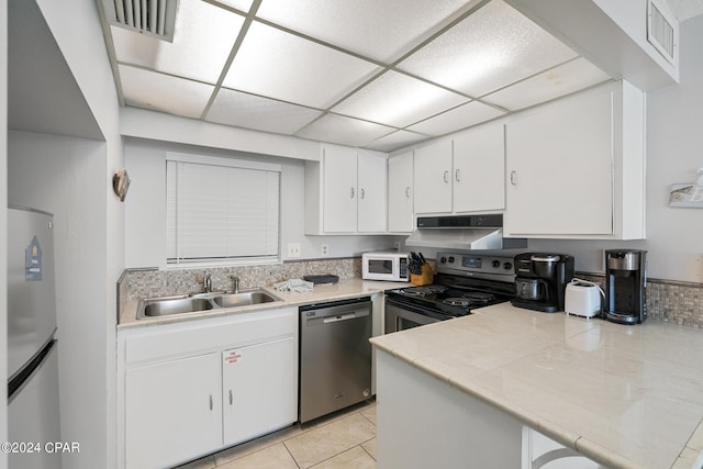 kitchen with stainless steel appliances, white cabinets, light tile patterned floors, and sink