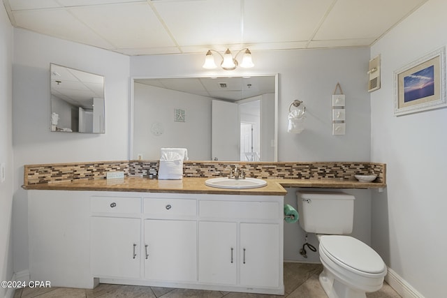 bathroom featuring a paneled ceiling, vanity, toilet, and tasteful backsplash