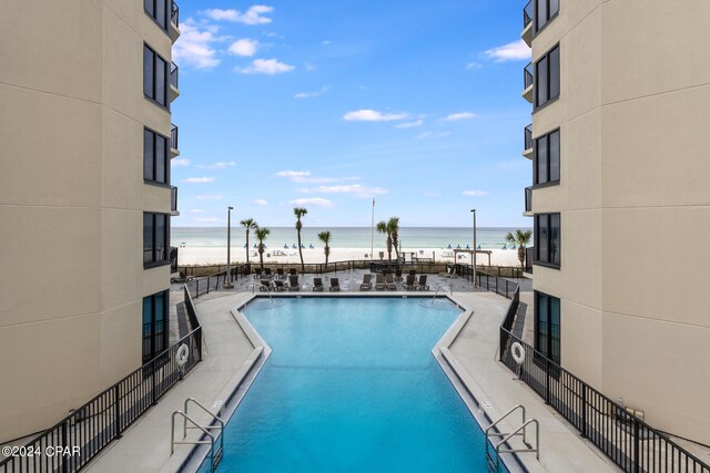 view of swimming pool with a view of the beach, a patio, and a water view