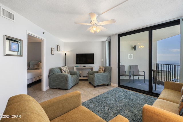 living room with a textured ceiling, light tile patterned floors, a wall of windows, and ceiling fan