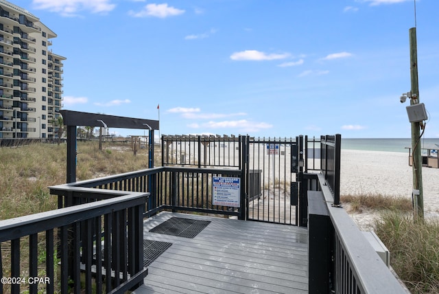 wooden deck featuring a water view and a view of the beach