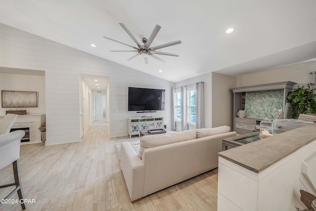 living room with a premium fireplace, light wood-type flooring, lofted ceiling, and ceiling fan