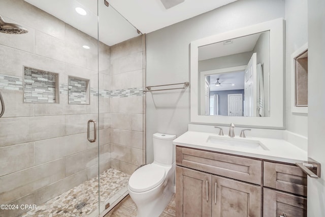 bathroom with vanity, toilet, ceiling fan, and a shower with door