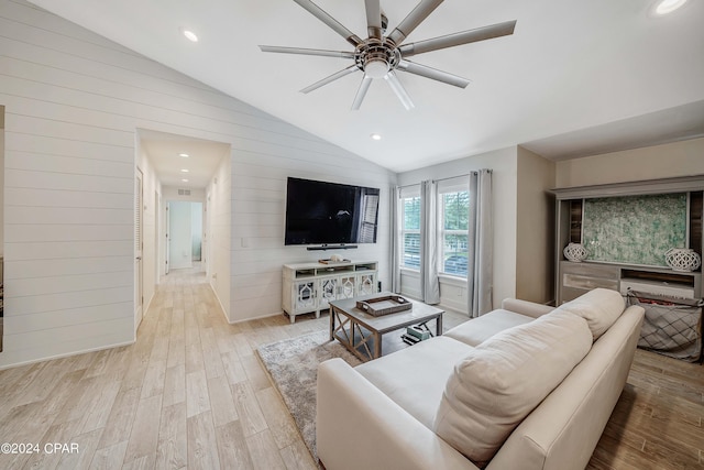 living room featuring wood walls, vaulted ceiling, ceiling fan, and light hardwood / wood-style flooring