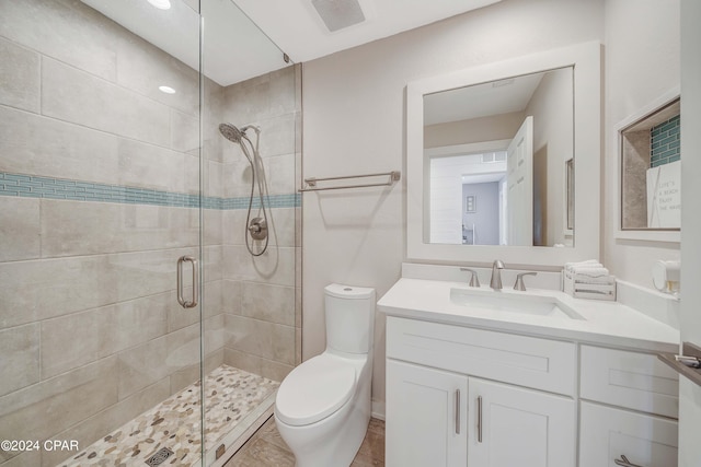 bathroom featuring vanity, a shower with shower door, and toilet