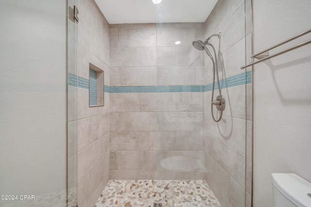 bathroom with a tile shower and toilet