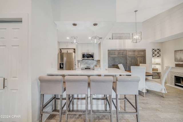 kitchen featuring pendant lighting, a breakfast bar area, stainless steel appliances, and white cabinets