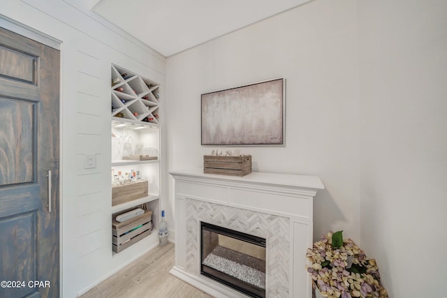 living room with indoor bar, a tiled fireplace, and light hardwood / wood-style floors