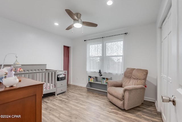 bedroom featuring ceiling fan, a closet, light hardwood / wood-style floors, and a crib