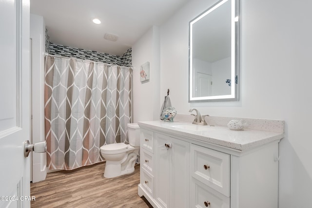 bathroom with hardwood / wood-style flooring, vanity, curtained shower, and toilet