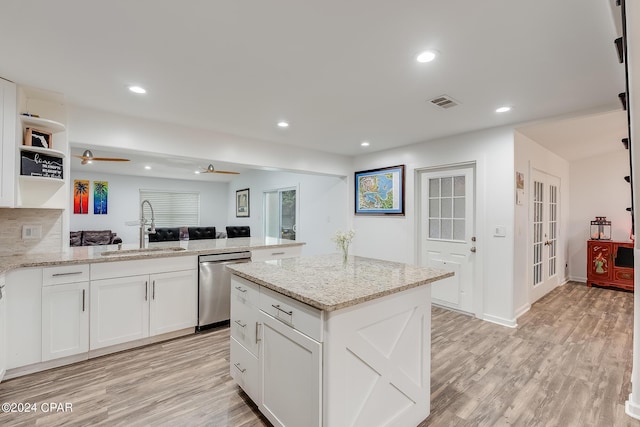 kitchen featuring white cabinets, sink, stainless steel dishwasher, light stone countertops, and kitchen peninsula