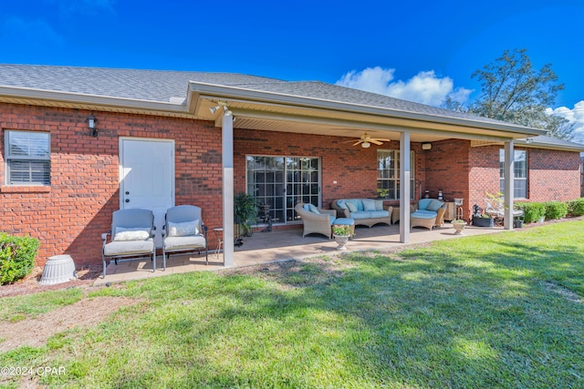 back of house with brick siding, a lawn, an outdoor hangout area, a patio, and a ceiling fan