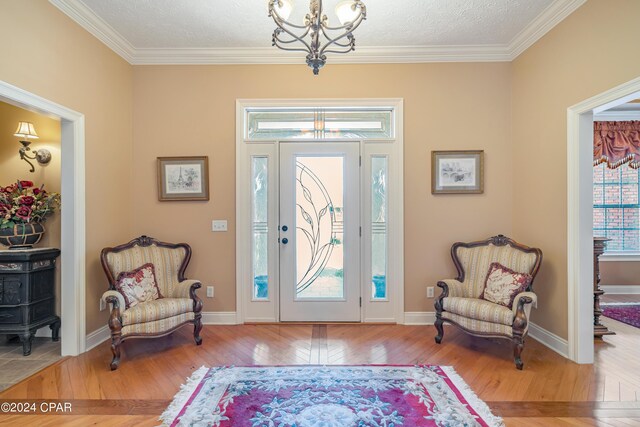 foyer featuring a chandelier, a healthy amount of sunlight, a textured ceiling, and hardwood / wood-style floors