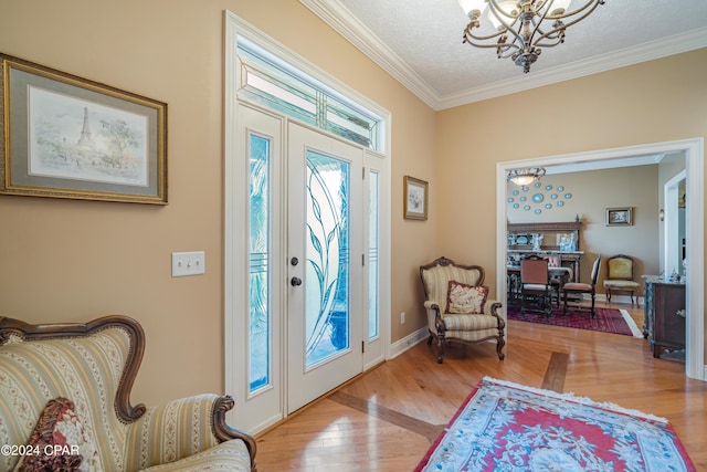 foyer with crown molding, baseboards, a chandelier, wood finished floors, and a textured ceiling