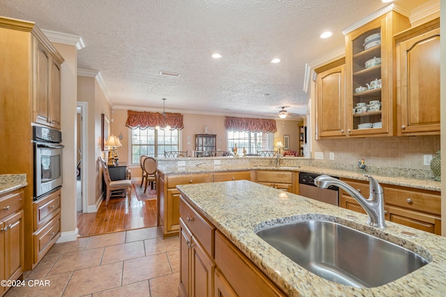 kitchen with visible vents, backsplash, crown molding, stainless steel oven, and a sink