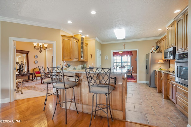 kitchen with backsplash, crown molding, a breakfast bar area, appliances with stainless steel finishes, and a peninsula