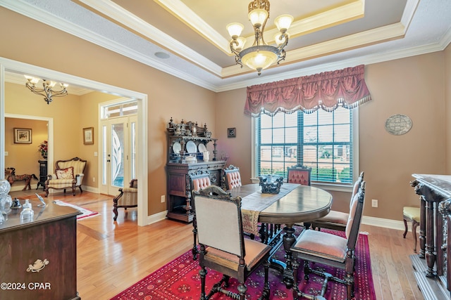 dining room with a notable chandelier, light wood-type flooring, and a tray ceiling