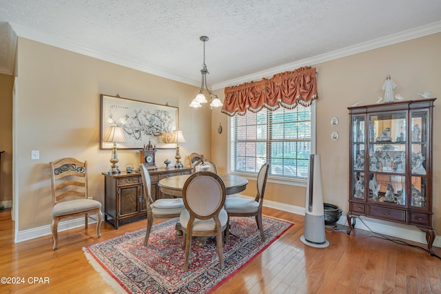 dining room with baseboards, light wood-style floors, ornamental molding, and a textured ceiling