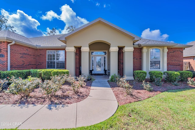 single story home with a front lawn, brick siding, roof with shingles, and stucco siding