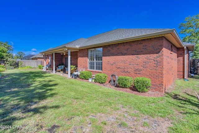 rear view of house with a patio, fence, ceiling fan, a lawn, and brick siding