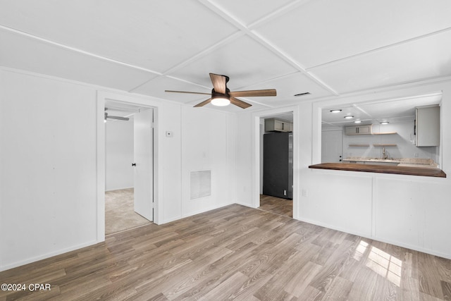 unfurnished living room featuring coffered ceiling, ceiling fan, light hardwood / wood-style flooring, and sink