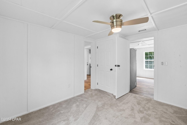 unfurnished bedroom featuring ceiling fan, light colored carpet, and coffered ceiling