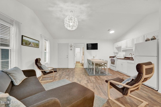 living room featuring a notable chandelier, light wood-type flooring, lofted ceiling, and sink