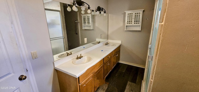 bathroom with wood-type flooring, a shower with shower door, and vanity