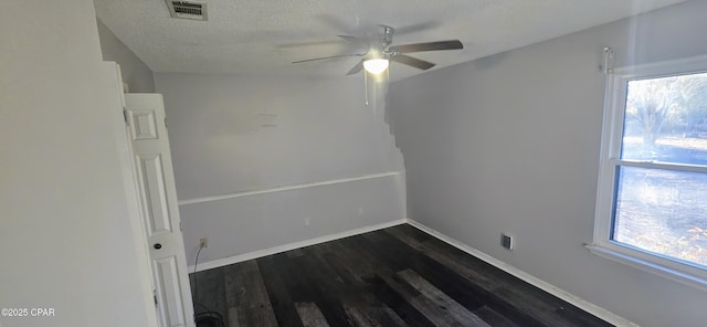 spare room with ceiling fan, plenty of natural light, dark hardwood / wood-style floors, and a textured ceiling