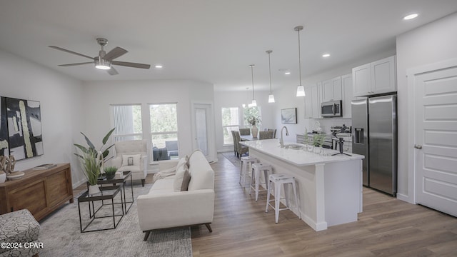 kitchen featuring white cabinetry, an island with sink, a breakfast bar area, stainless steel appliances, and ceiling fan