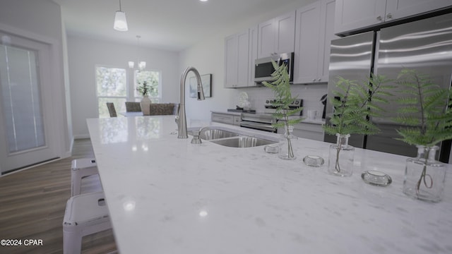 kitchen with pendant lighting, light stone countertops, dark wood-type flooring, and stainless steel appliances