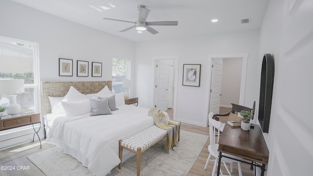 bedroom featuring ceiling fan, light hardwood / wood-style floors, and multiple windows